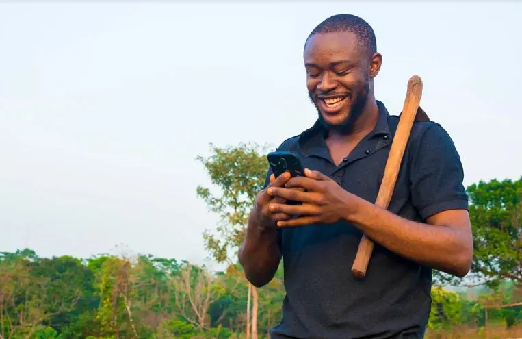 A farmer smiling at his phone